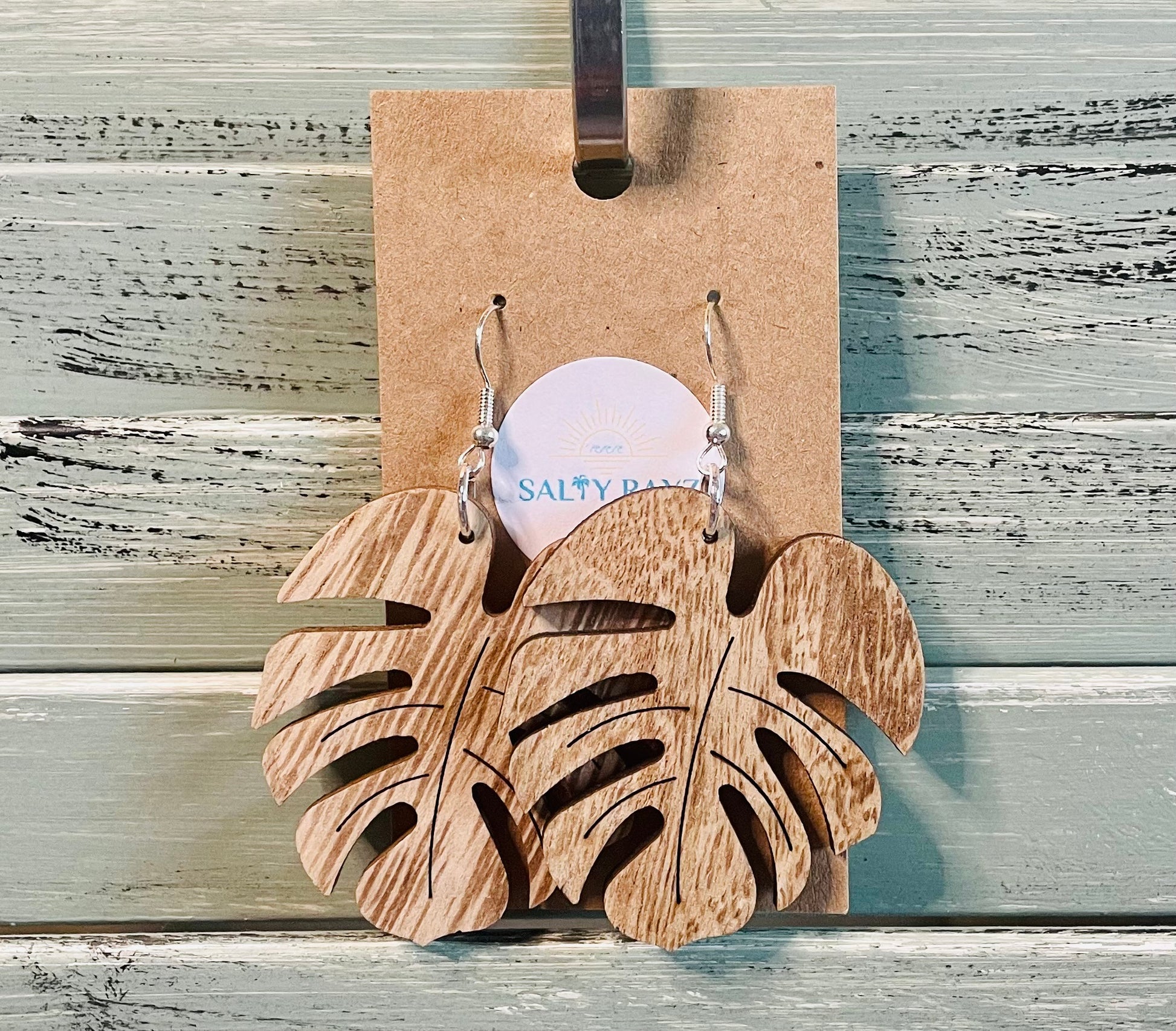 Wooden leaf-shaped earrings on a cardboard backing with 'Salty Bae' branding.