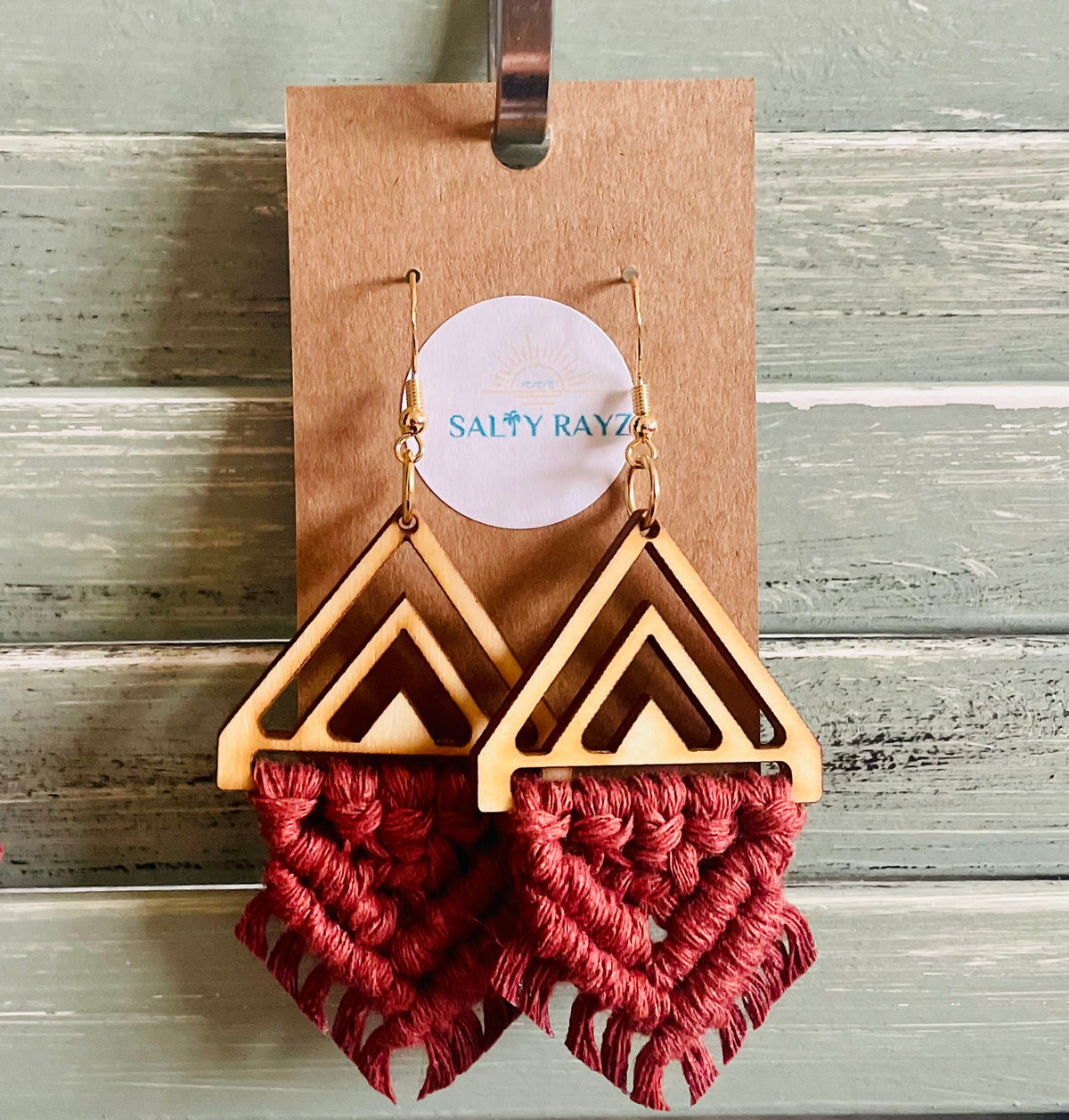 Wooden earrings with red macrame details on a wooden stand with 'Sally Rayz' branding.
